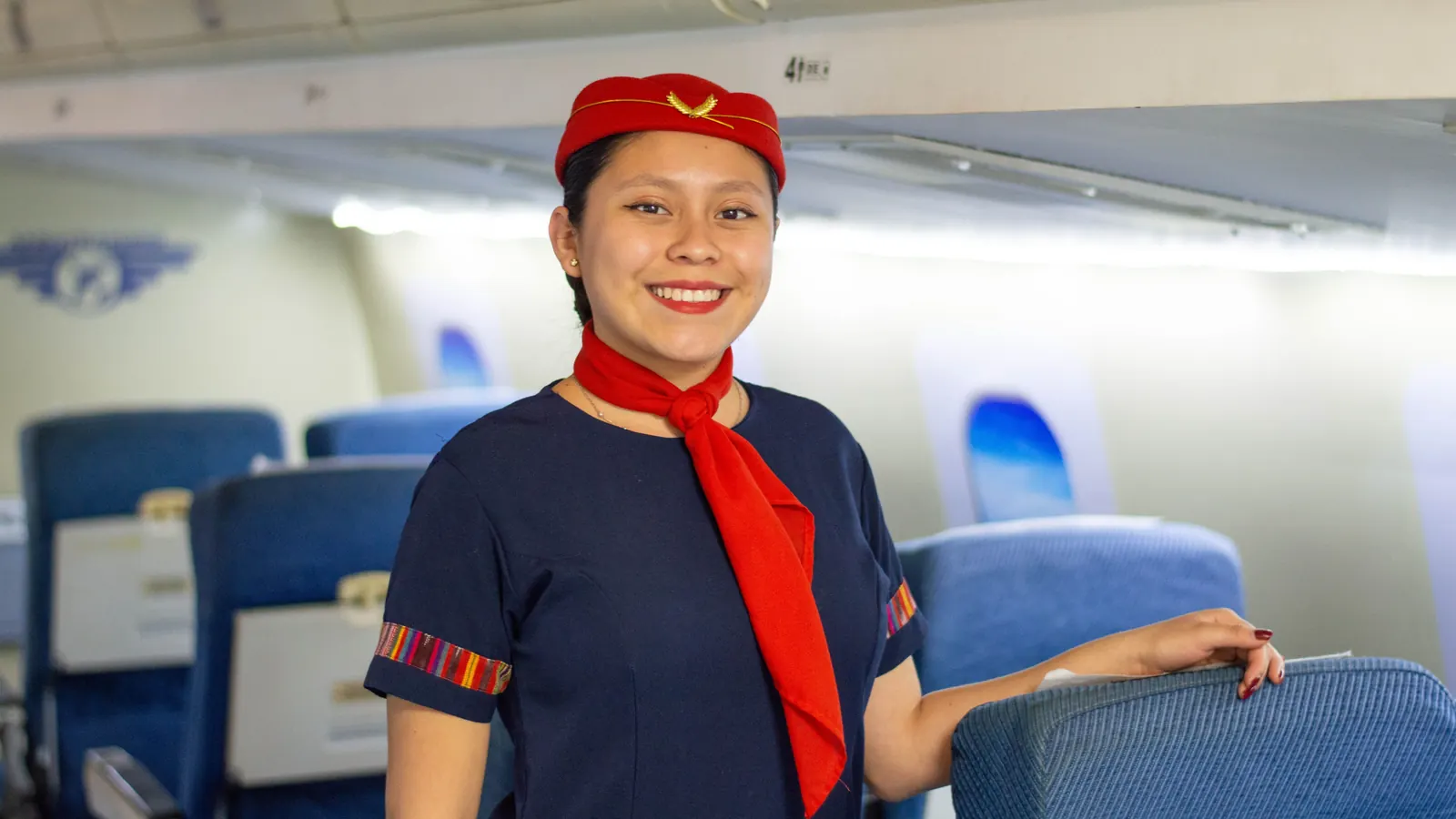 Smiling flight attendant in uniform standing in the aisle of an aircraft cabin
