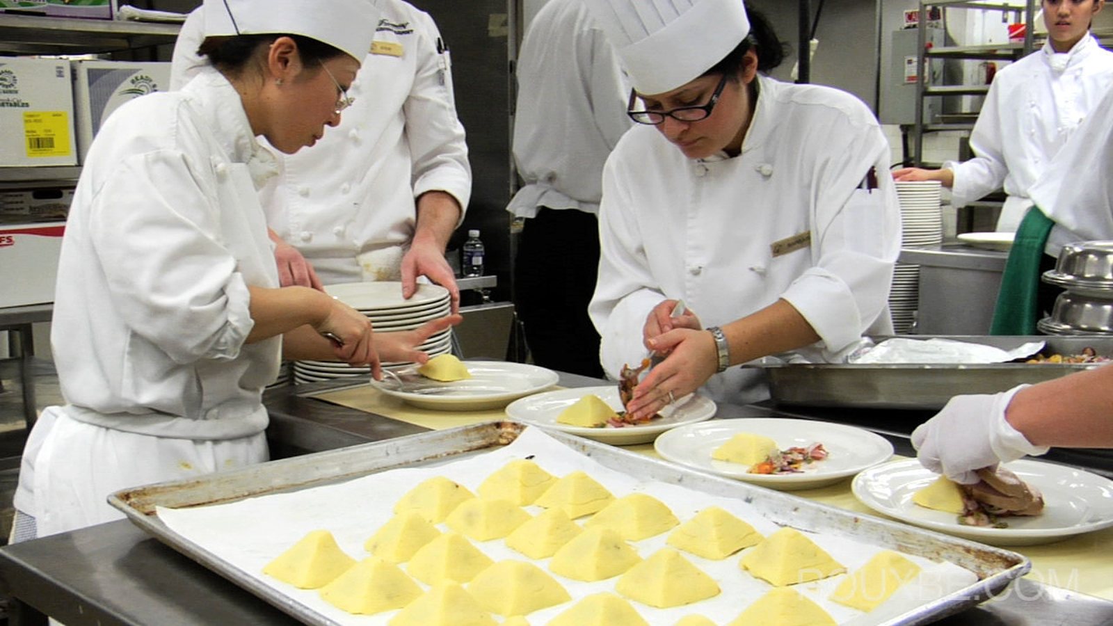 Chefs in white uniforms working together in a professional training kitchen